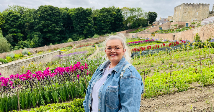 woman smiling at camera with The Auckland Project Walled Garden in the background.